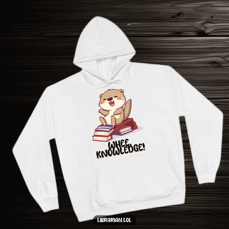 Funny, delighted otter sliding down a ramp constructed from books, featured on a soft hoodie, embodying playful literary adventure.
